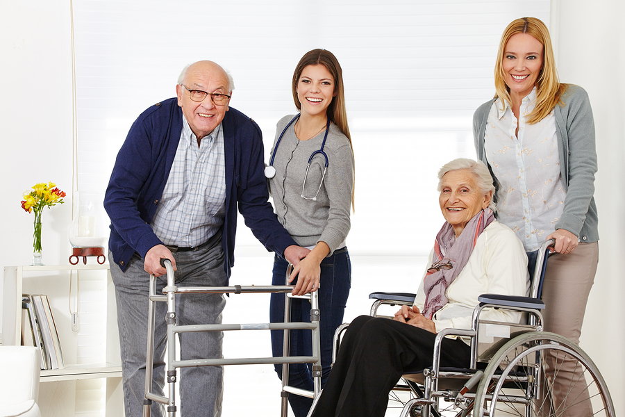 Woman with senior couple at home getting help from a caregiver