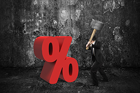 Businessman holding sledgehammer hitting red percentage sign with dark concrete room background